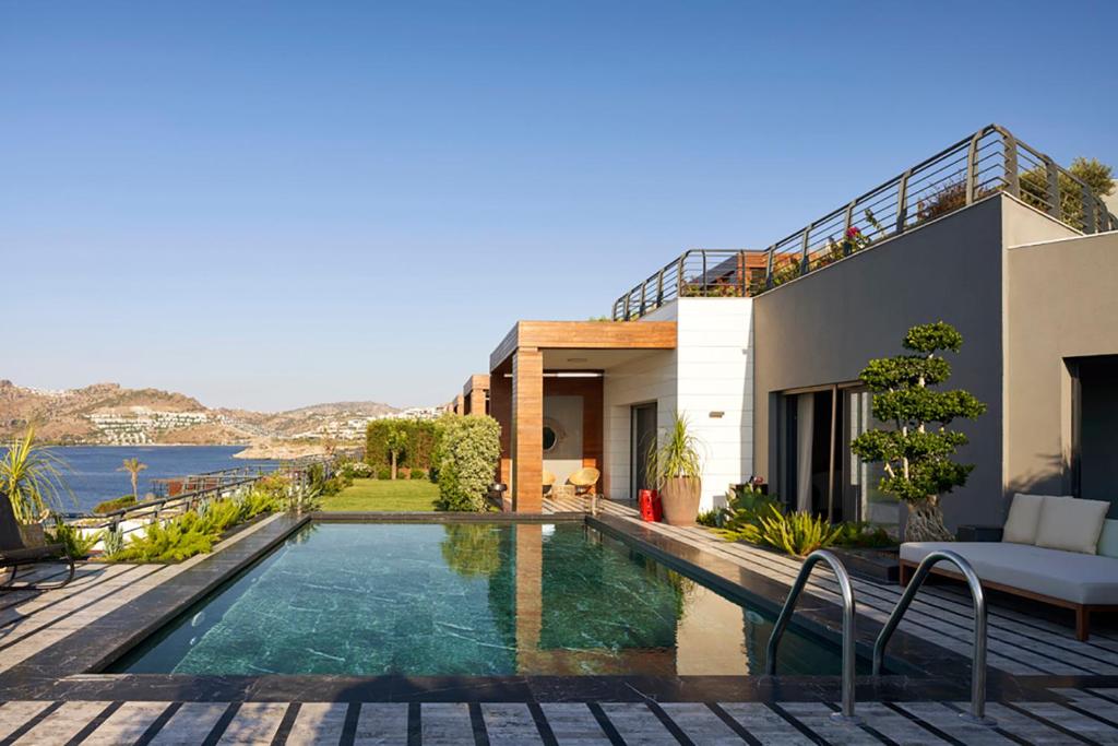 a villa with a swimming pool in front of a house at Root Redrock Yalıkavak in Bodrum City