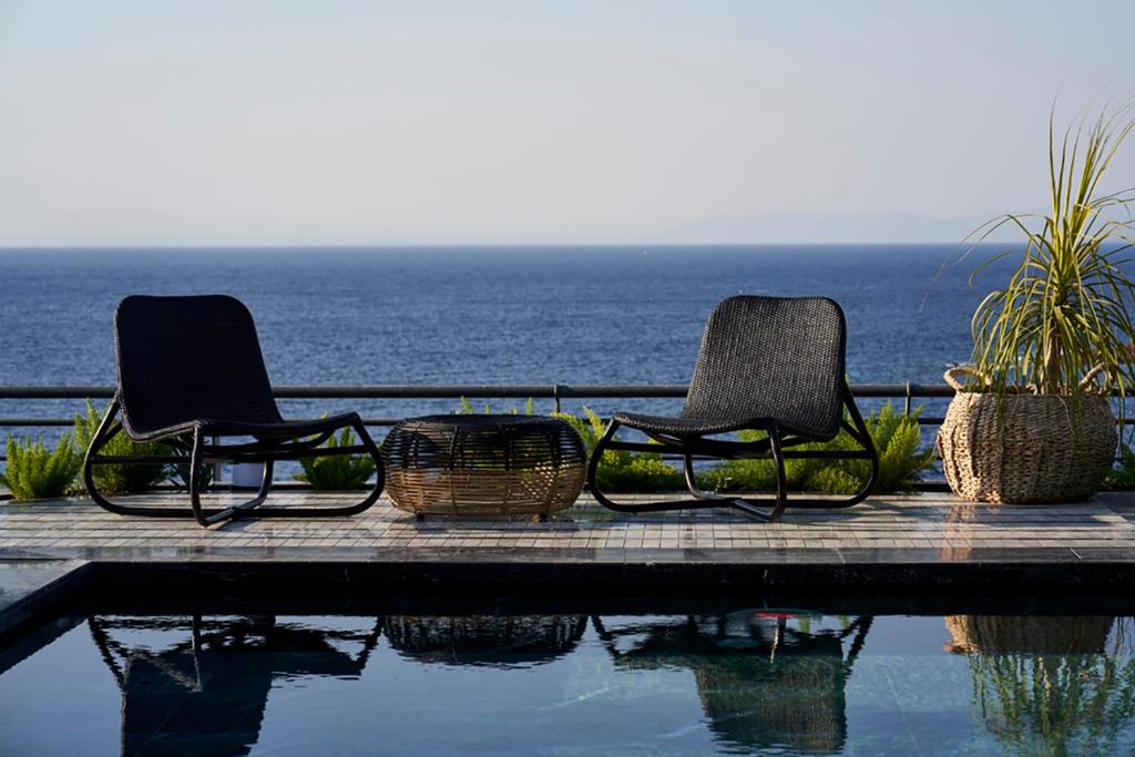 two chairs sitting next to a pool near the ocean at Root Redrock Yalıkavak in Yalıkavak