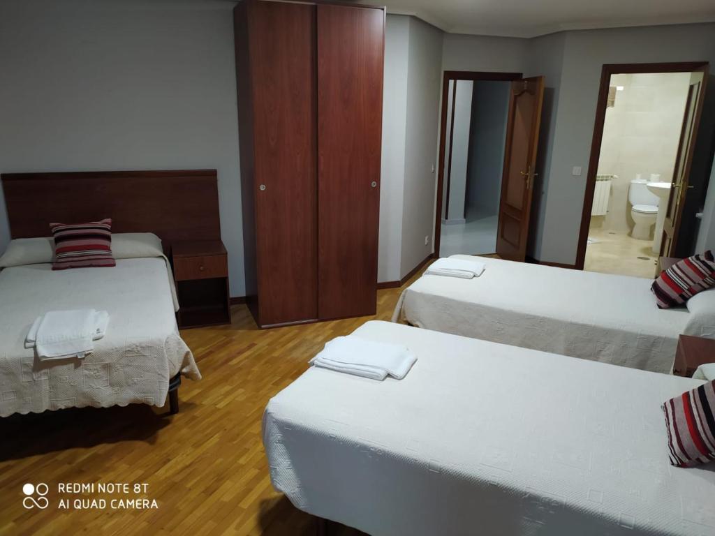 Habitación de hotel con 3 camas y espejo en Hostal Cerecedo, en León