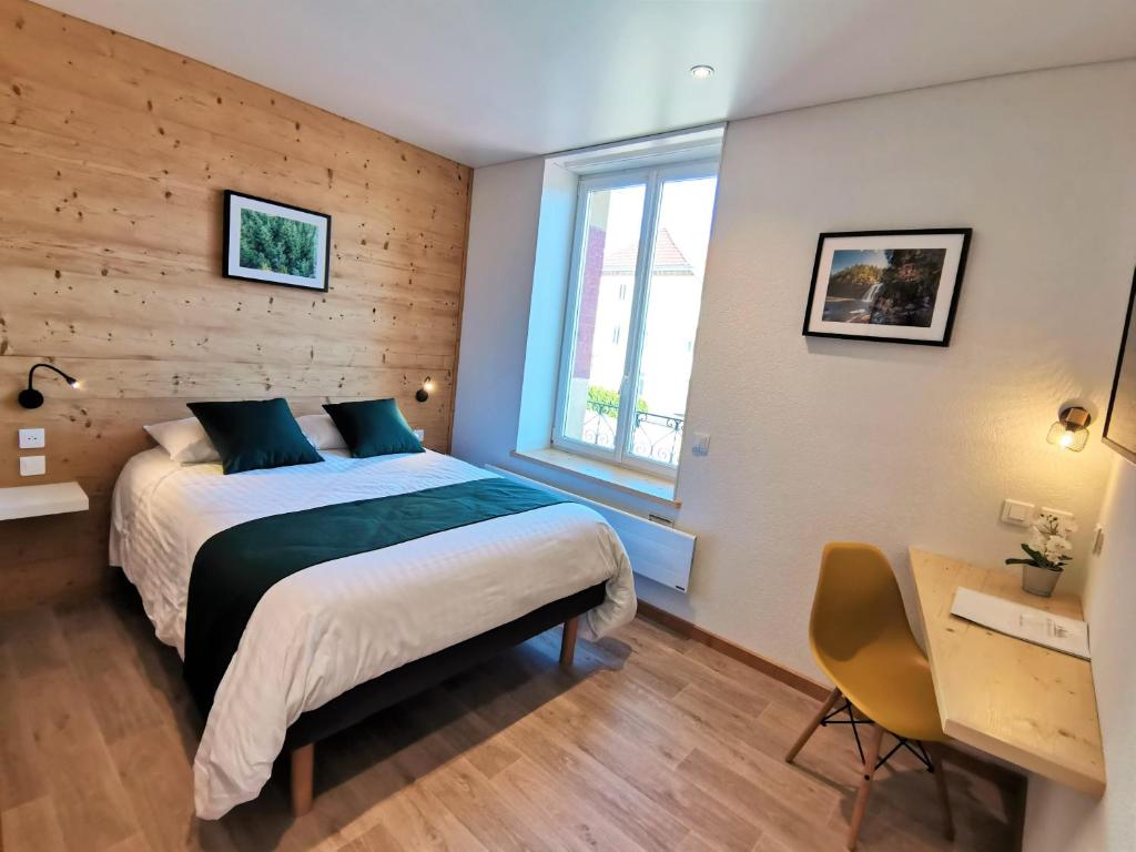 1 dormitorio con cama, escritorio y ventana en Hotel Les Montagnards en Morteau