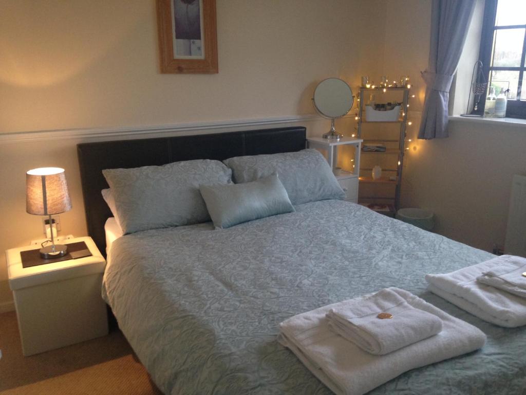 een slaapkamer met een groot bed en handdoeken bij Jen's Friendly Place in Dudley