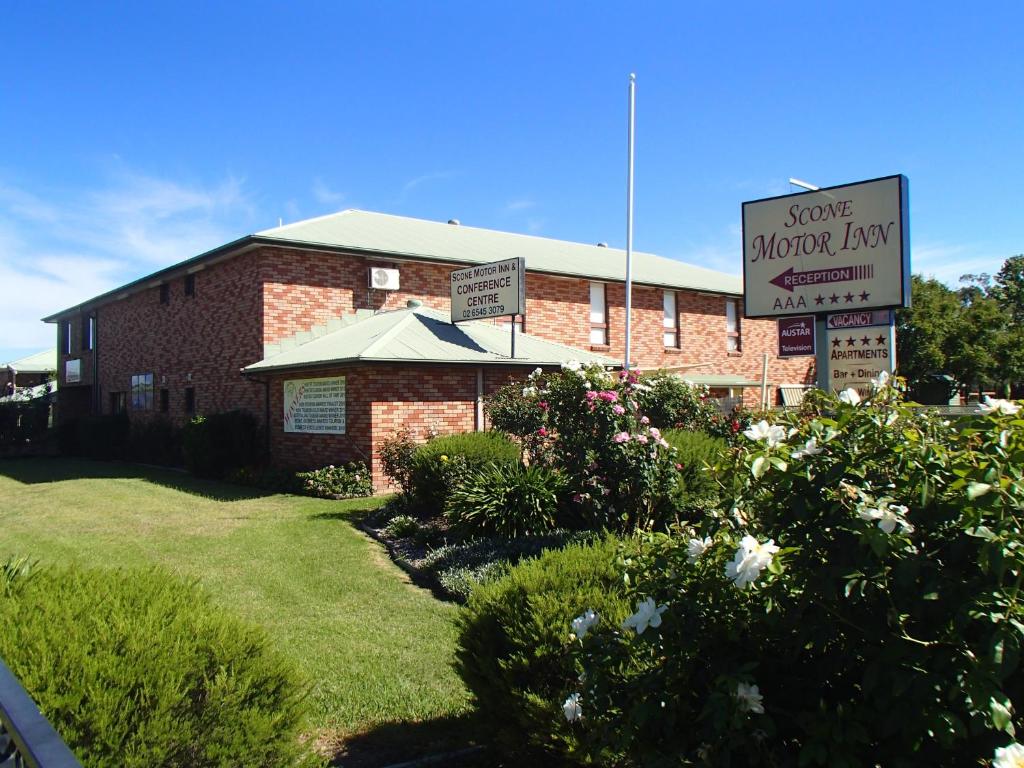 um edifício de tijolos com um sinal para uma loja de flores lenta em Scone Motor Inn & Apartments em Scone