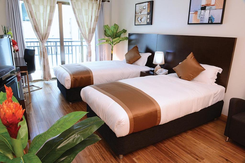 two beds in a hotel room with a room at Timor Plaza Hotel & Apartments in Dili