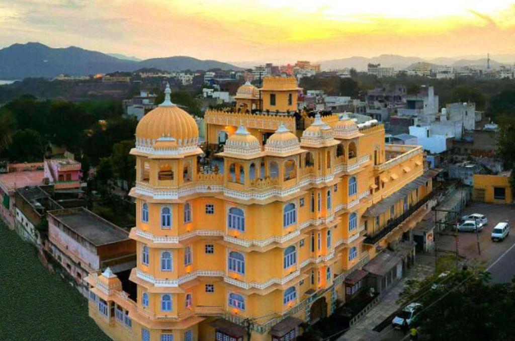 un grande edificio giallo con una cupola sopra di Bloom Boutique l A Heritage Property at Lake Pichola a Udaipur