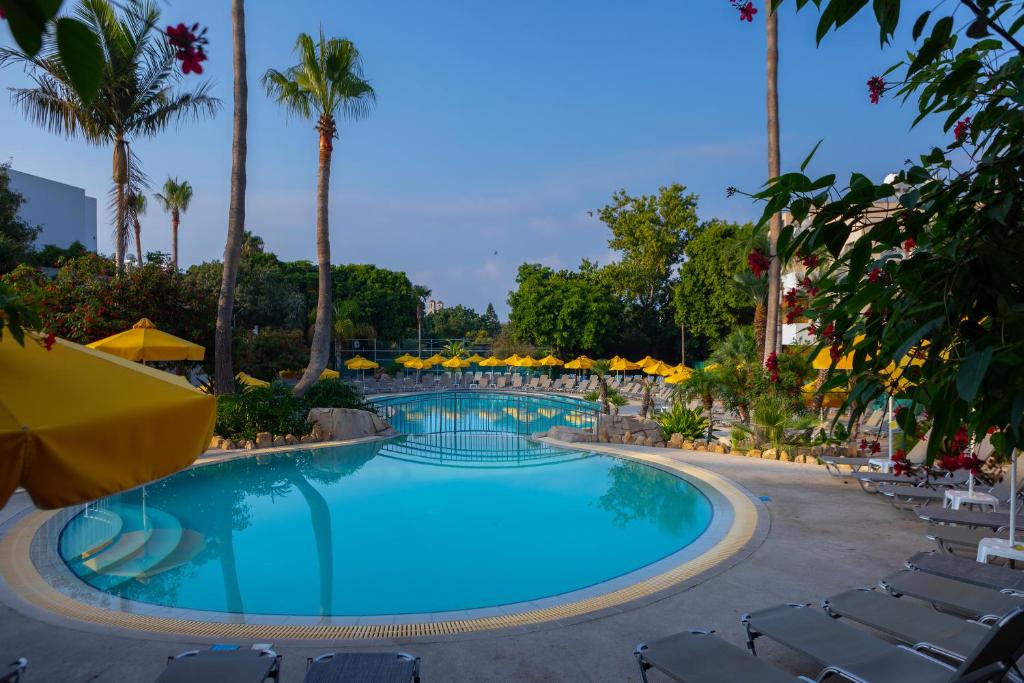 una piscina en un complejo con sillas y palmeras en Mayfair Gardens, en Pafos