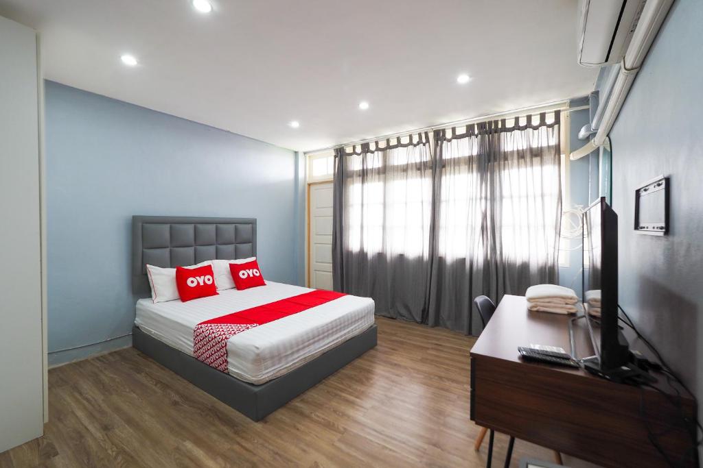 Schlafzimmer mit einem Bett, einem Schreibtisch und einem TV in der Unterkunft OYO 615 Bossa House Hostel & Cafe in Bangkok