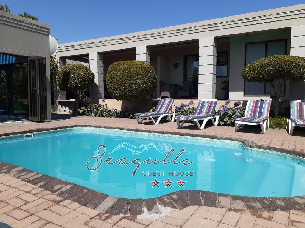 a swimming pool in front of a guest house at Seagulls Guest House in Langebaan
