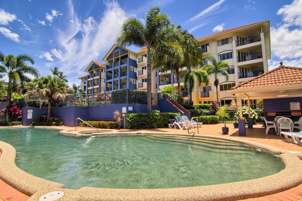 a pool in front of a building with palm trees at North Cove Waterfront Suites in Cairns