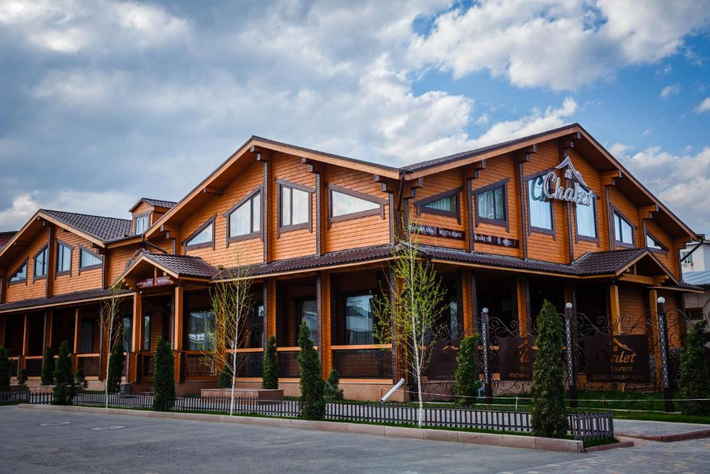 un gran edificio de madera con un cartel. en Guest House Chalet, en Taraz