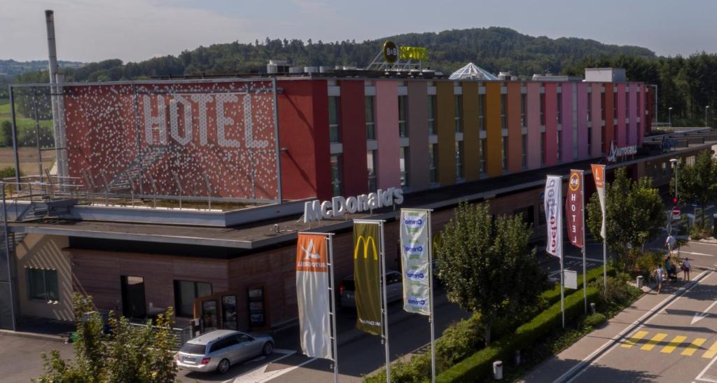 a building with a car parked in front of it at B&B HOTEL Lully 3 Lakes in Estavayer-le-Lac