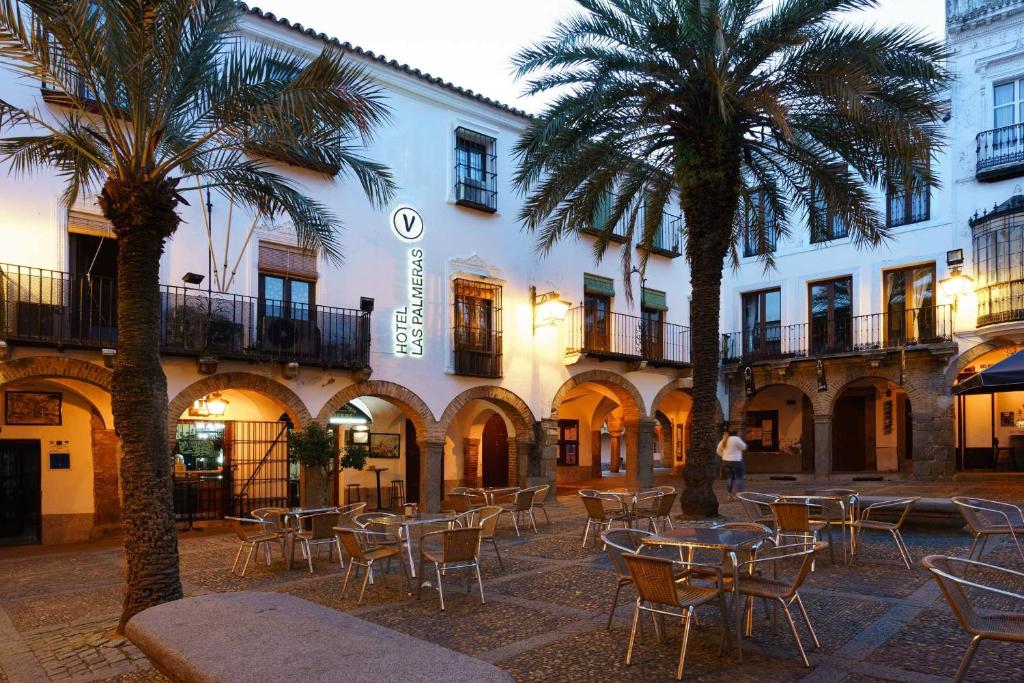 une cour avec des tables et des palmiers devant un bâtiment dans l'établissement Hotel Las Palmeras by Vivere Stays, à Zafra