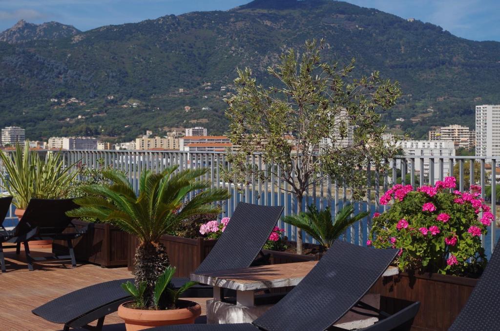 a balcony with tables and potted plants and a mountain at Hôtel Spunta Di Mare in Ajaccio