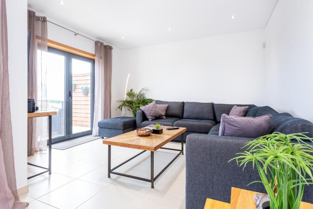 Una sala de estar con un sofá azul y una mesa. en Casa Chic, en Vila do Bispo