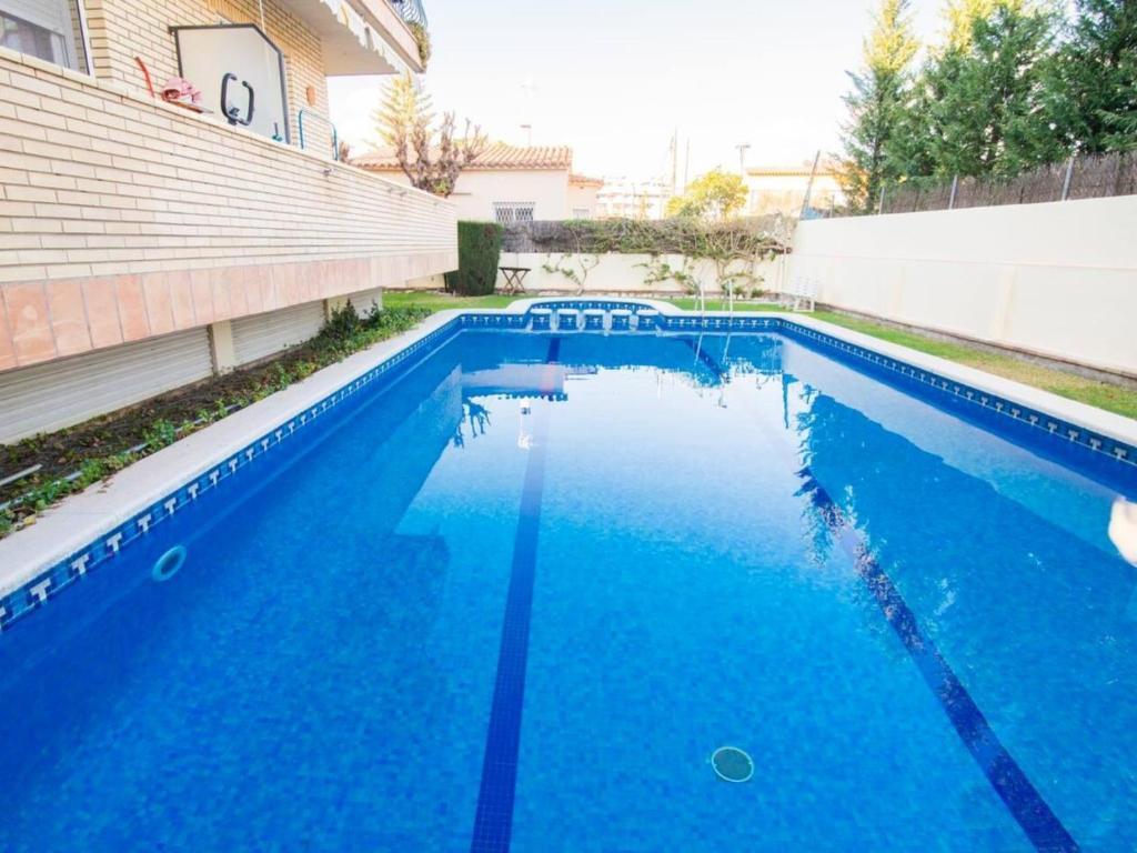 einem Pool mit blauem Wasser vor einem Gebäude in der Unterkunft Sunny apartment 3 blocks to the beach in Castelldefels