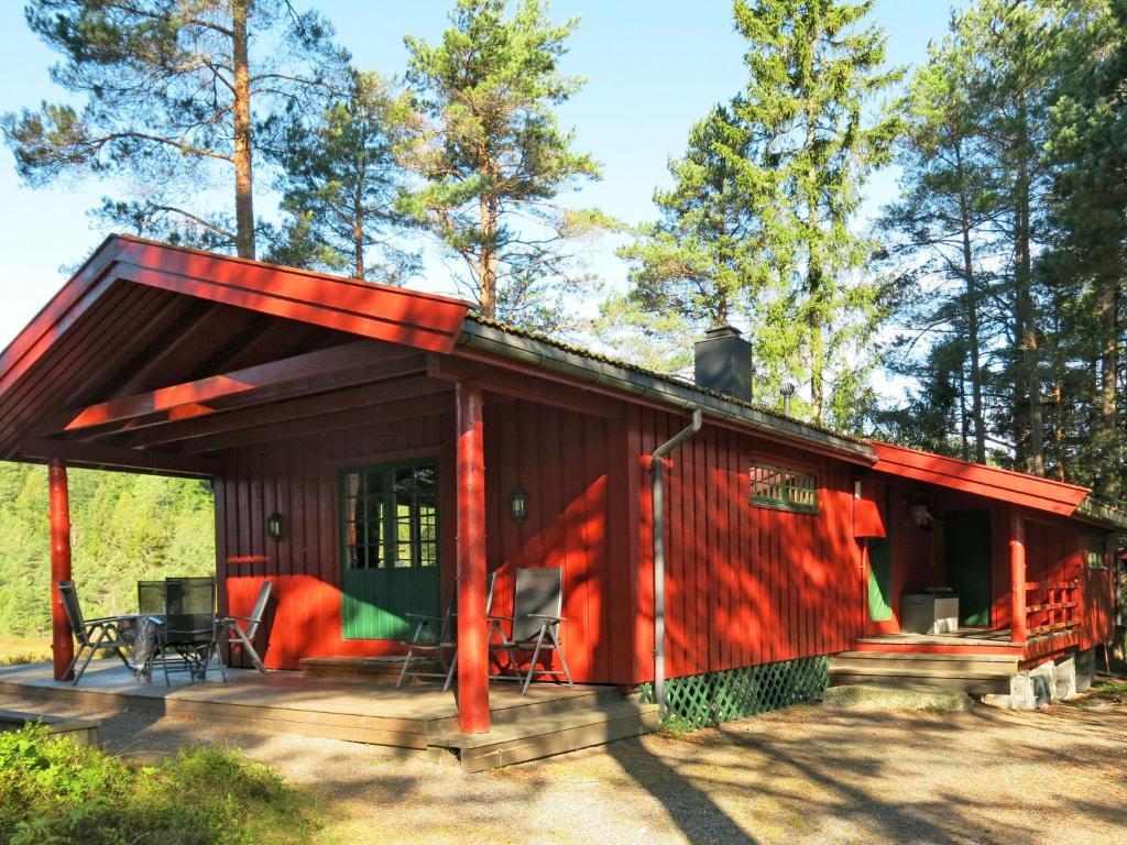 una cabaña en el bosque con techo rojo en Chalet Holmestua - SOO398 by Interhome en Arendal