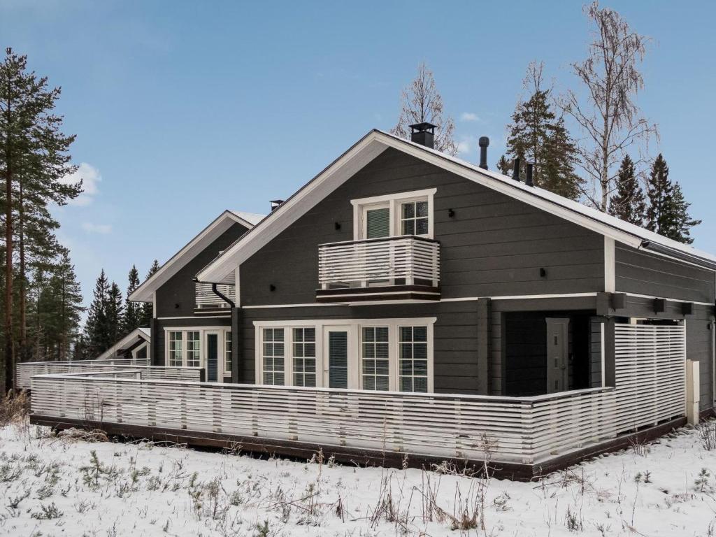 a black house with a porch in the snow at Holiday Home Leimu a by Interhome in Vuokatti