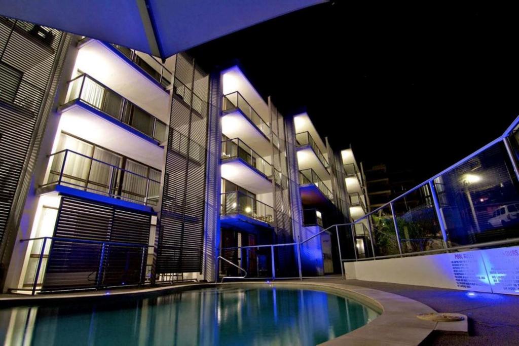 a swimming pool in front of a building at night at Merrima Court Holidays in Caloundra