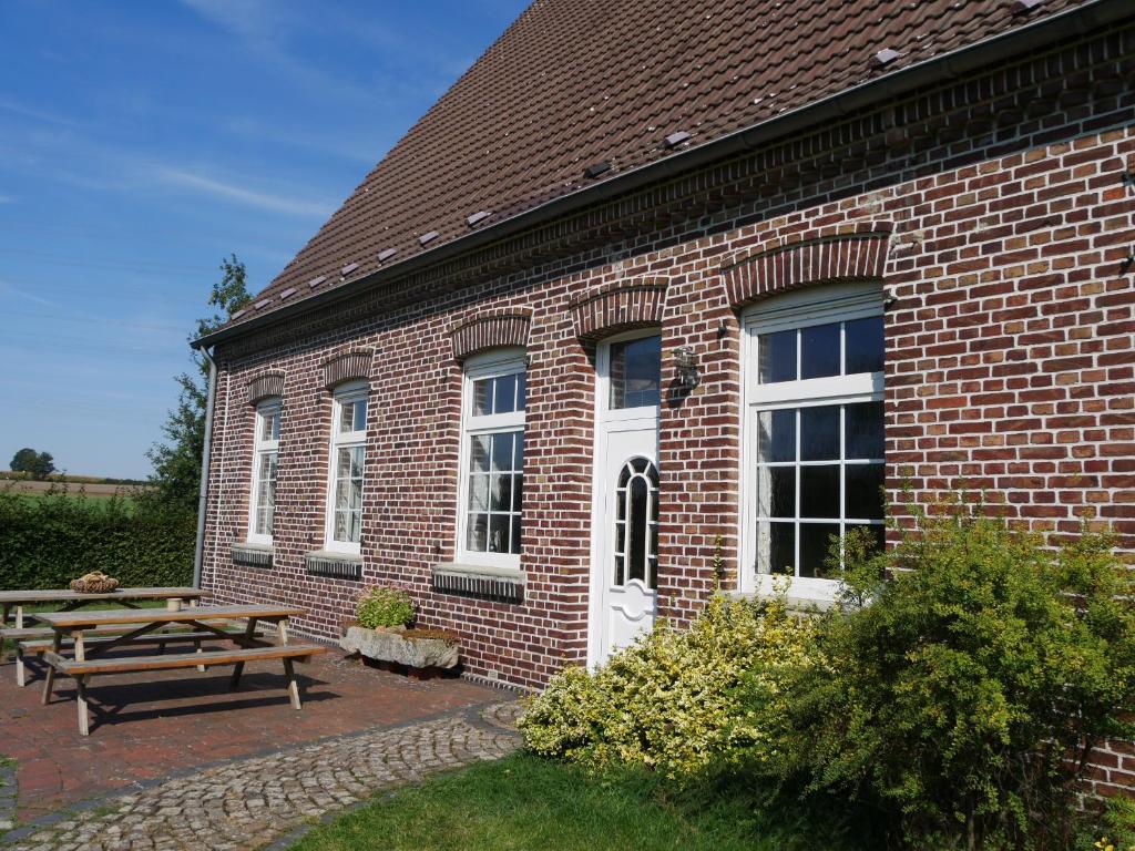 ein Backsteingebäude mit einem Picknicktisch und einer Bank in der Unterkunft Landhaus Holthausen in Werne an der Lippe