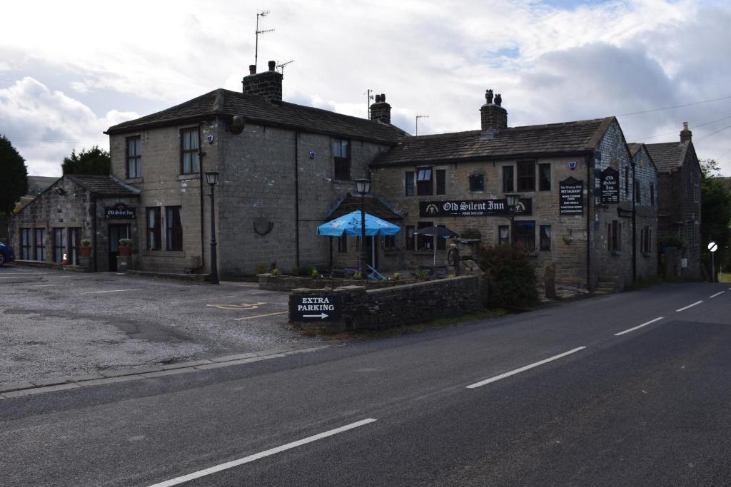 um edifício antigo ao lado de uma rua em The Old Silent Inn em Haworth