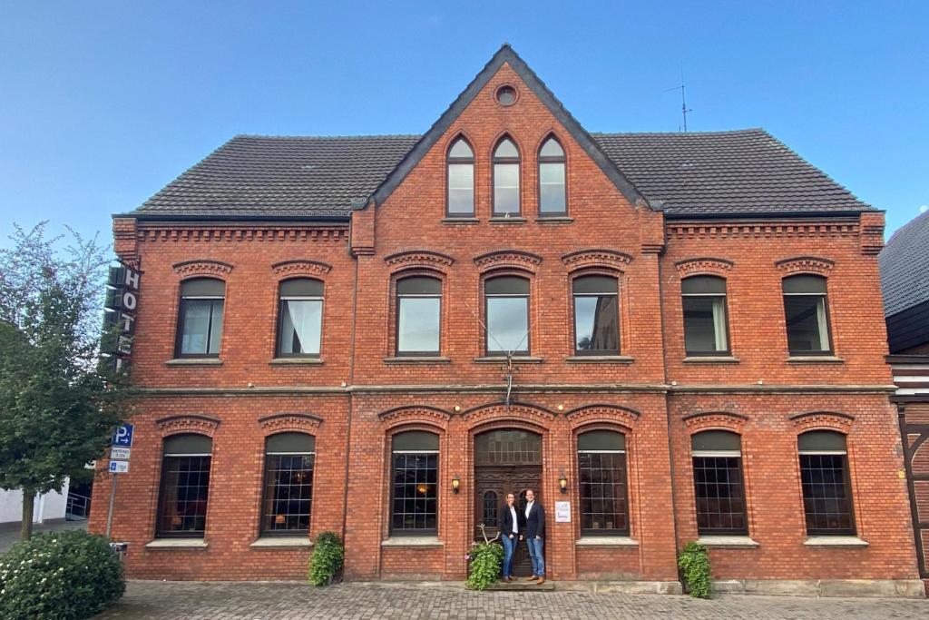 dos personas de pie en frente de un edificio de ladrillo en Hotel Wolfsjäger, en Herbern