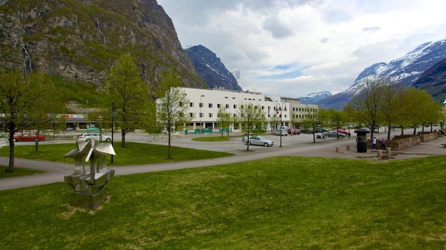 a park with a building and a street with mountains at Sunndalsøra Hotell in Sunndalsøra