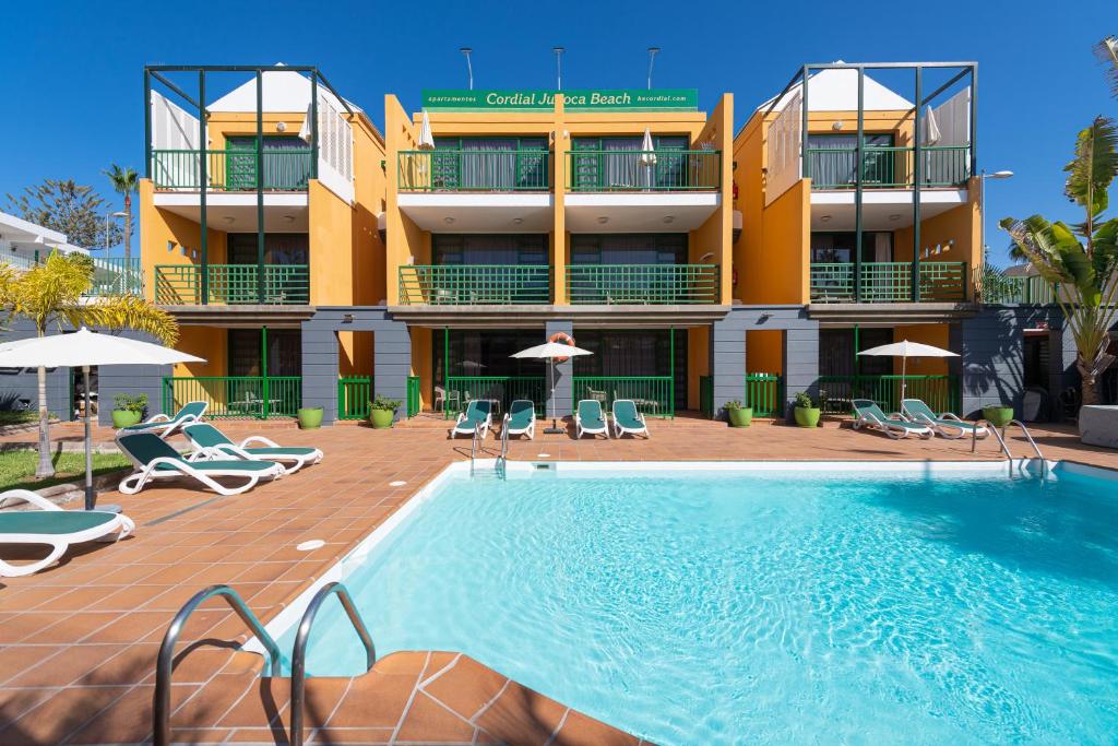 un hotel con piscina di fronte a un edificio di Apartamentos Cordial Judoca Beach a Playa del Ingles
