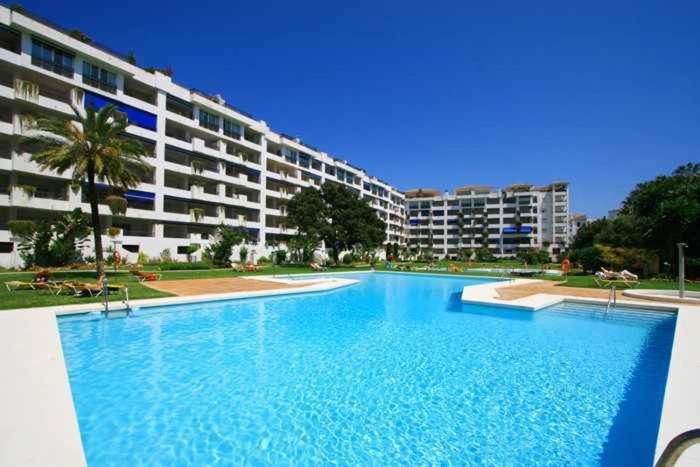 una gran piscina frente a un gran edificio en Ground Floor apartment in the heart of Puerto Banús, en Marbella