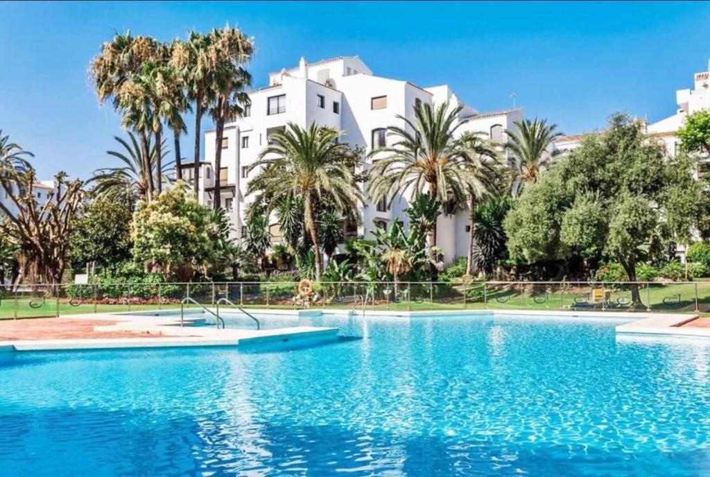 een groot zwembad voor een groot wit gebouw bij Apartamento en Jardines del Puerto in Marbella