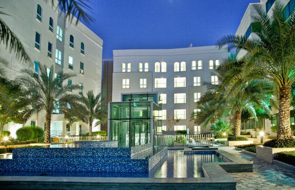 a large building with a large pool of water at Millennium Executive Apartments Muscat in Muscat