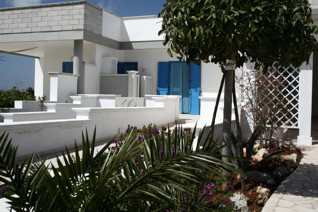 a white house with blue doors and a palm tree at Villa Giulia in Ostuni