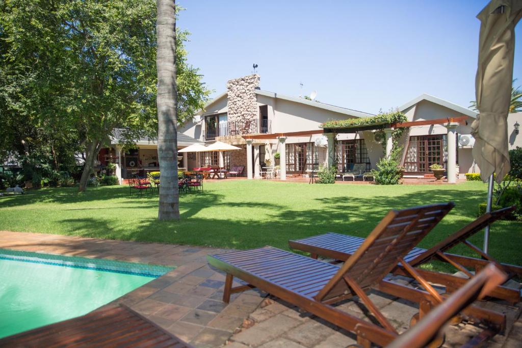 uma piscina com uma cadeira ao lado de uma casa em MacGregors Guest House em Pretoria