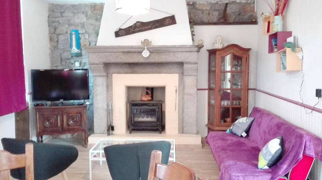 ein Wohnzimmer mit einem lila Sofa und einem Kamin in der Unterkunft Maison de 2 chambres avec jardin clos et wifi a Sourdeval in Sourdeval