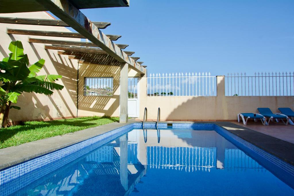 a swimming pool with chairs next to a building at Villa Lovisi 2 in Playa del Ingles