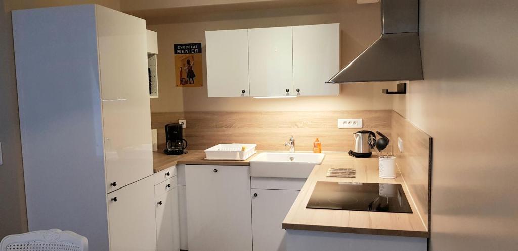 a small kitchen with white cabinets and a sink at La maison Virginie logements de 1 à 5 pers chaleureux centre, parking, linge, wifi, proximité lac canal piscine in Montargis