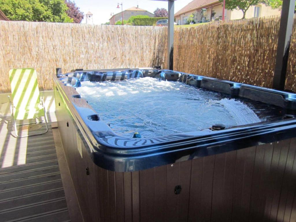 a hot tub in a backyard with a fence at Maison avec spa à They-Sous-Montfort, accueillant et moderne in They-sous-Montfort