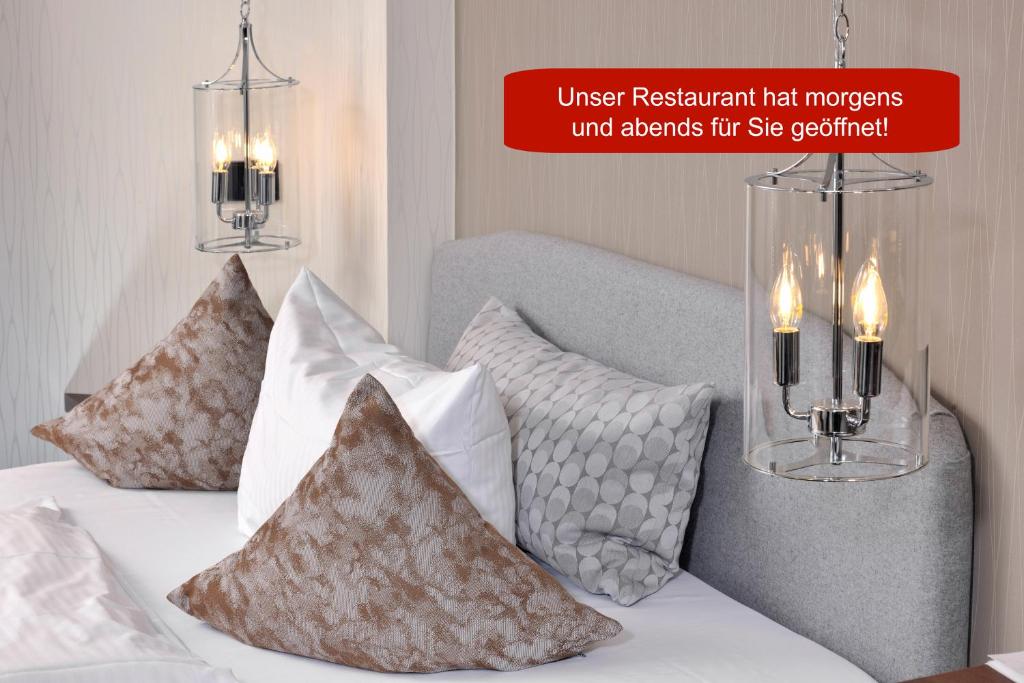 a bedroom with a bed with pillows and two chandeliers at Lobinger Hotel Weisses Ross in Langenau