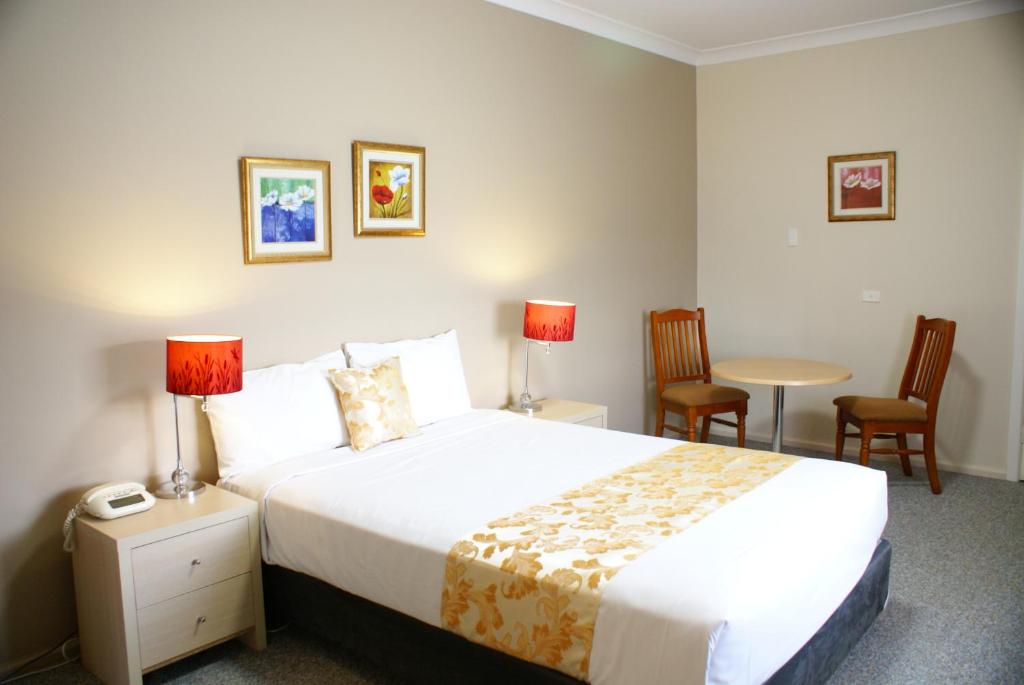 a hotel room with a bed and a table and chairs at Country Lodge Motor Inn in Bathurst
