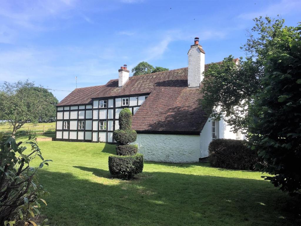 an old house with a hedge in front of it at Tickeridge Farm in Hanley Castle