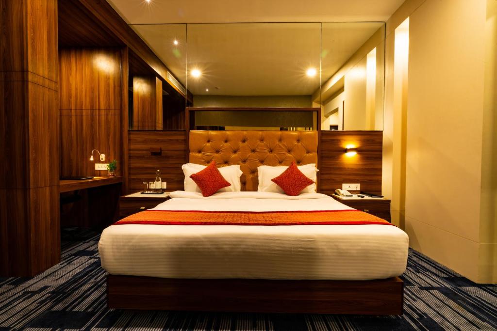 a hotel room with a large bed with red pillows at Regenta Inn Morbi in Morbi