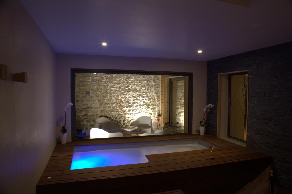 a room with a bath tub with a stone wall at Le Clos Des Coteaux in Trigny