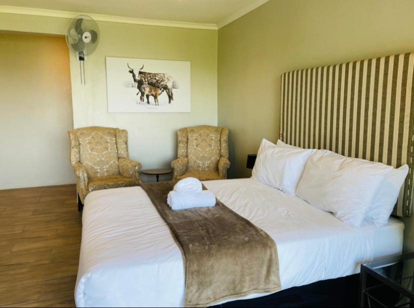 a hotel room with a bed and two chairs at Ollivanders Estate in KwaNgendezi