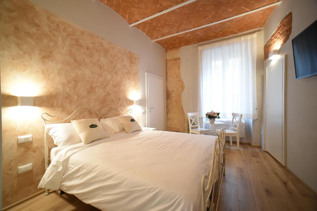 Un dormitorio con una cama blanca y una mesa. en Casa Martimbola Self Check-in, en Arezzo