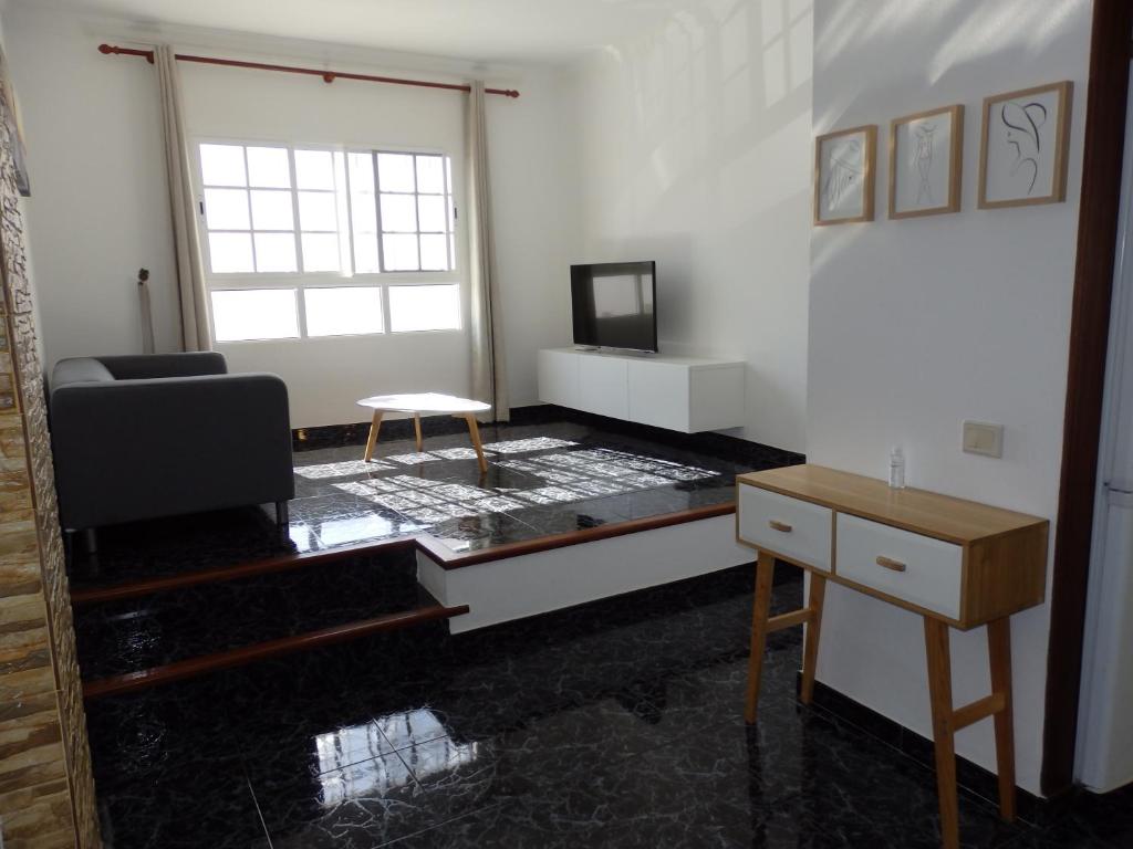 ein Wohnzimmer mit einem Sofa, einem Stuhl und einem Tisch in der Unterkunft Toni's in Arinaga