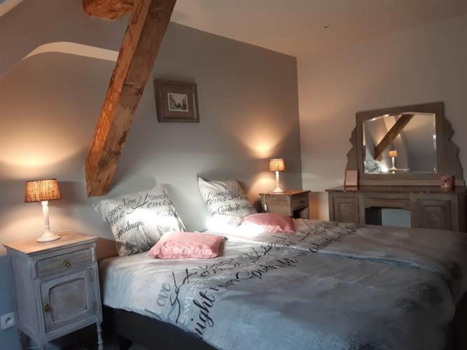 een slaapkamer met een bed met 2 kussens en een spiegel bij Le Maffe de Scourmont in Chimay