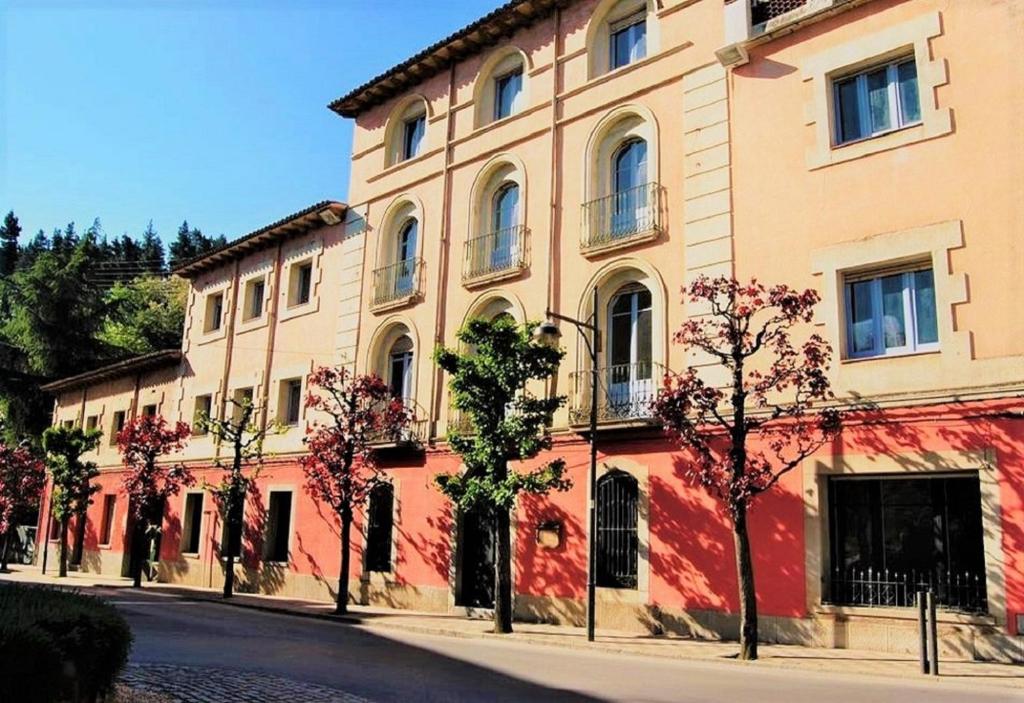 a large building with trees in front of a street at Hostal Montsoliu in Arbúcies