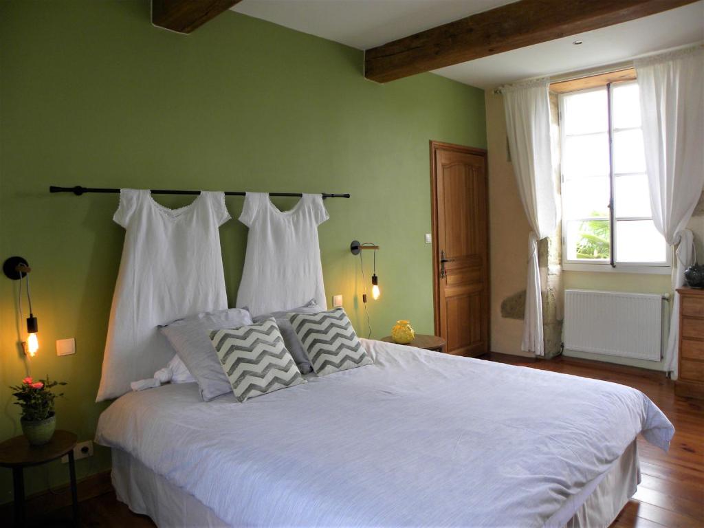 een slaapkamer met een groot bed met witte lakens en kussens bij Maison Olleris in Couloumé-Mondébat