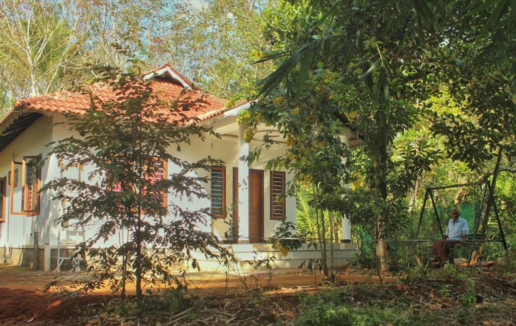 a man sitting in front of a white house at Wayanad Days in Mananthavady