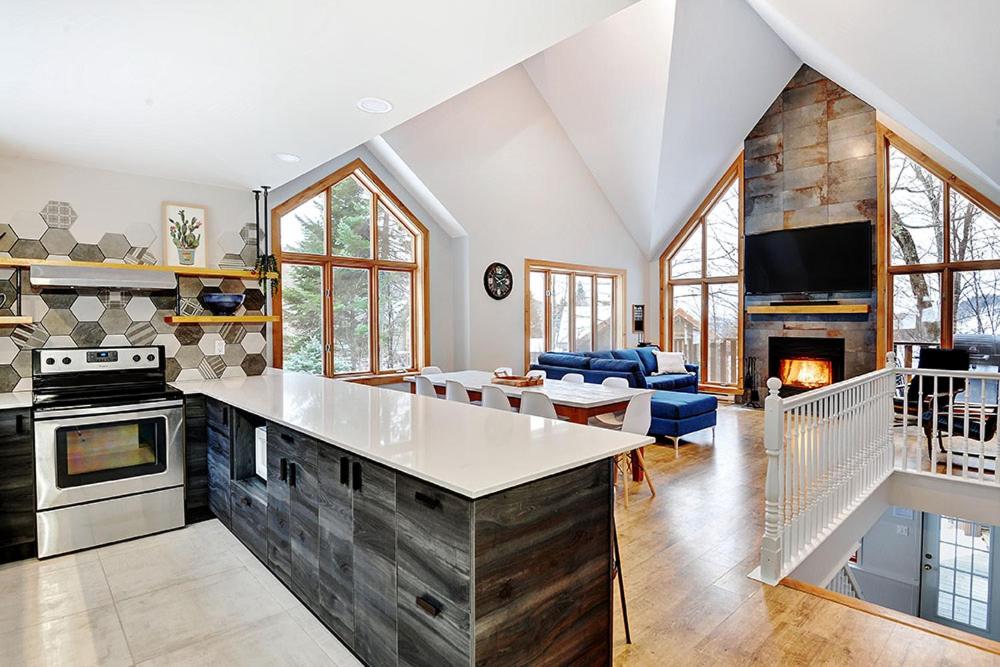 a large kitchen and living room with a fireplace at Chalets Alpins- 4 Chemin des Montagnards in Stoneham