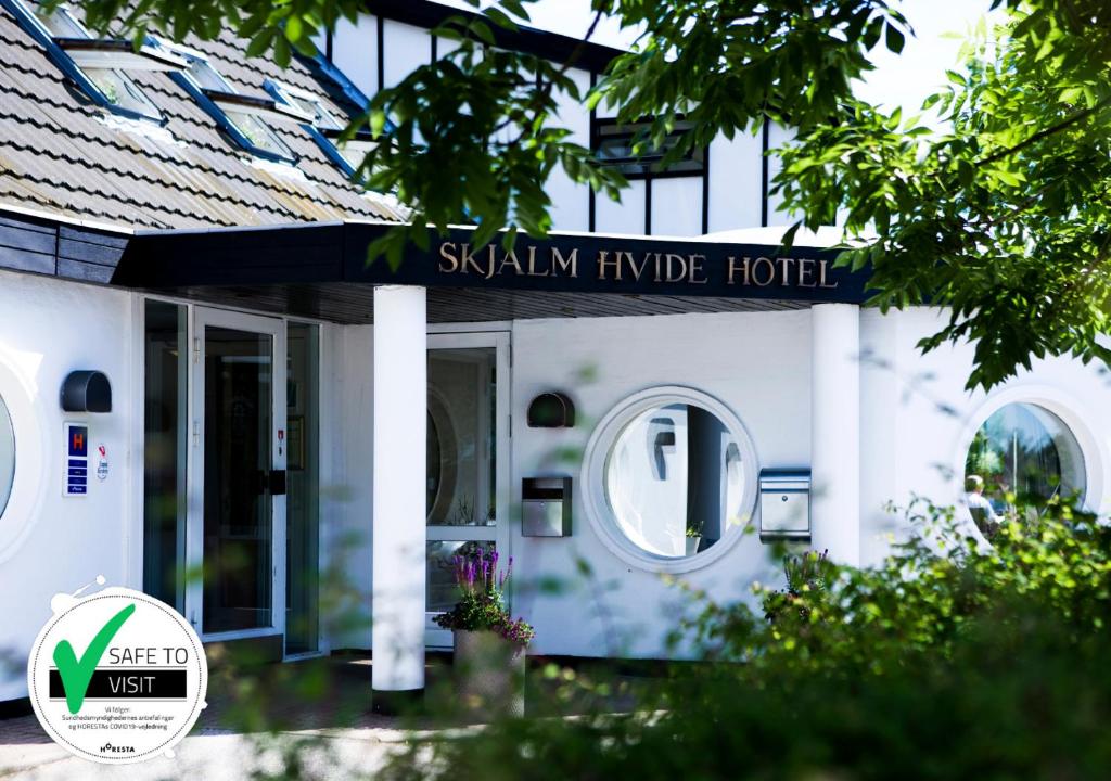 Skjalm Hvide Hotel في Slangerup: بيت ابيض مع لافته مكتوب عليها فندق skymym مثلث