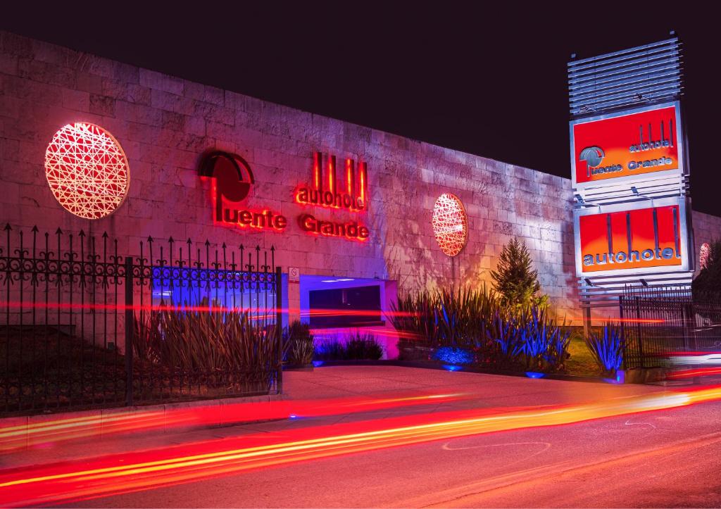 een gebouw met 's nachts neonborden bij Hotel Puente Grande in Las Ánimas